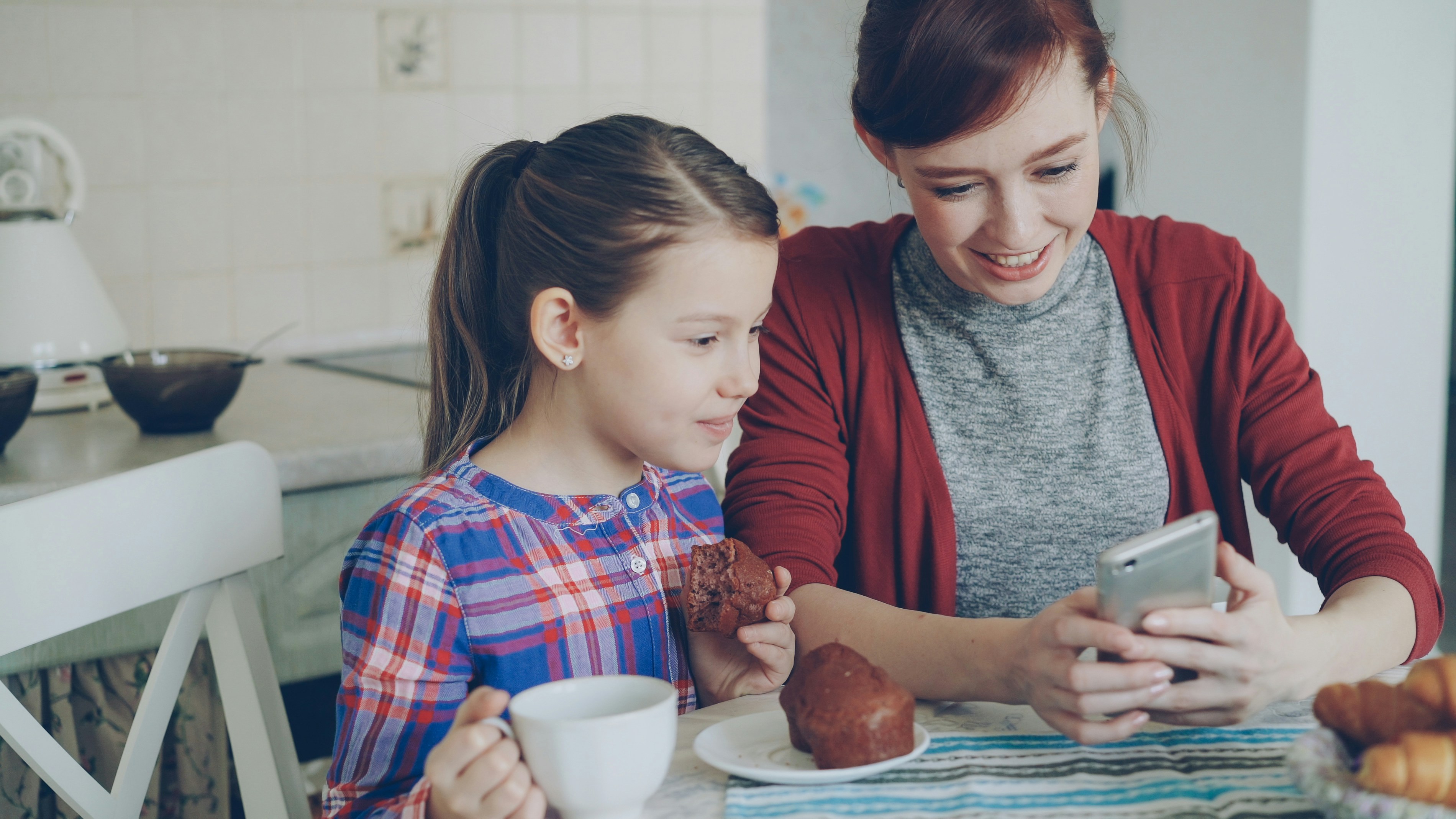 A parent and child reading together on a phone